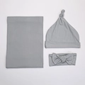 Close-up of soft grey knit baby swaddle set including a knotted hat and bow headband - Gray