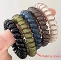 Close-up of flexible spiral phone cord hair ties in assorted matte neutral colors - Fruit Green
