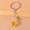 Close-up of a creative glow-in-the-dark conch shell keychain with resin pendant - Orange