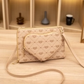 Beige Monogram crossbody bag with heart pouch and golden zipper on wooden table - Apricot