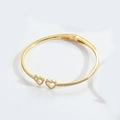 Dettaglio del bracciale dorato aperto con ciondoli a cuore e intarsio in zircone - Doppio cuore / Oro