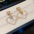 Détail de boucles d'oreilles cœur dorées avec cristaux sur un coussin à bijoux - Aiguille Argentée N° 18 - Or - Cœur