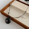 Dettaglio della collana in corda intrecciata con pendente a croce vintage su velluto - Collana Nera / Nero