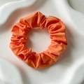 Solid orange cotton scrunchie with soft fabric pleats on a white ceramic tray - Orange