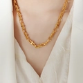 Collana a maglie grosse in acciaio al titanio dorato con sfere indossata da modella - Collana Oro