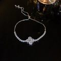 Macro shot of silver adjustable bracelet featuring clear zircon clover on black mirror - Silver