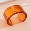 Close-up view of amber marble acrylic cuff bracelet featuring a chunky fashion design - Cuff Bracelet / Brown