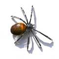 Macro detail of a metal spider ornament featuring a polished oval tiger eye stone body - Oval Tiger's Eye