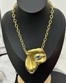 Detailed close-up of a surrealist gold face pendant with a blue eye on a thick Cuban chain - Gold Necklace