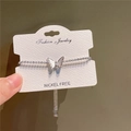 Detailopname van sprankelende vlinderarmband met nikkelvrije kaart op groene achtergrond - Zilver
