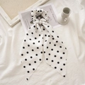 Vista dettagliata di un elastico a pois con nastri lunghi su sfondo di tessuto bianco - Pois Bianco Con Nastro