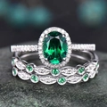 Macro shot of luxury oval green emerald rings with pavé diamonds on textured stone - US 7 / White Gold