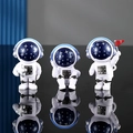 Tre statuine di astronauti in resina bianca con caschi stellati blu in varie pose - Cielo Stellato (Versione Ascolto)
