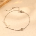 Minimalistische zilveren titanium stalen kruisarmband met zirkoon op beige lederen achtergrond - Staal Kleur Kruis Armband