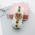 Detailed macro view of heart-shaped gold watch with red crystals and quartz dial - Gold Red