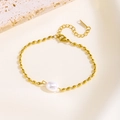 Detail of a gold beaded bracelet featuring a white pearl on a textured stone background - Rice Bead Chain Pearl Style