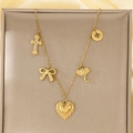Dettaglio della collana in titanio dorato con ciondoli a fiocco, croce, elefante e cuore - Stile Croce e Elefante con Stella (KN292156-SXSJ)