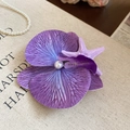 Dettaglio del fermaglio orchidea viola con stella marina e perle su tessuto beige - Stile Fiore Viola