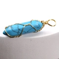 Handcrafted hexagonal turquoise pendant with gold wire wrapping on a white pedestal - Turquoise