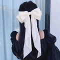 Elegant cream satin bow hair clip with long ribbons shown on model's hair - White