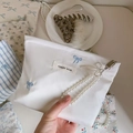 Dettaglio della borsa in tessuto bianco con ricamo fiocco blu e manico in perle - Base Bianca Fiocco Ricamato
