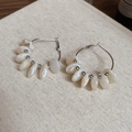 Detail of silver hoop earrings with white resin beads on natural linen background - White