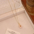 Close-up of a gold oval natural stone pendant necklace on a jewelry tray display - Rose Quartz