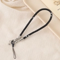 Close-up of a sparkling black rhinestone wrist strap with a silver metal clasp for bags - Black