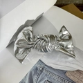 Close-up of a silver metallic fabric bow hair clip on a book and denim background - Silver Gray