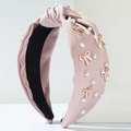Close-up of pink knotted fabric headband with pearl accents and alloy bow detail - Pink