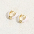 Elegant gold huggie earrings with light pink enamel finish on white stone background - White