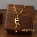 Titanium steel gold letter E pendant necklace with tassel displayed on walnut wood - Letter E / Gold