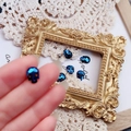 Macro shot of dark blue faceted skull stud earring with red eyes and gothic style - Mineral Blue
