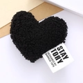 Detail shot of a black plush heart accessory with a designer fabric label on white background - Lamb Velvet Heart / Black