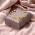 Detailed view of a gold infinity knot open cuff bracelet on a velvet jewelry box - Infinity Style (S280-1)