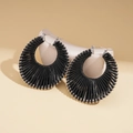 Detail of bohemian black woven hollow geometric round hoop earrings on a beige stand - Small / Black