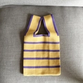Detailed texture of yellow and purple striped knit tote bag on a gray fabric sofa - Yellow Stripes