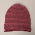 Detailtextuur van ademende mesh gebreide beanie met franjes en rolrand in pruimroze - Rozerood