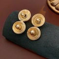 Vista macro di orecchini a doppia spirale dorata con sfere su espositore nero - Perno in acciaio inossidabile - Oro