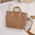 Dettaglio della borsa tote in velluto marrone con rivetti in metallo su sfondo bianco - Cammello