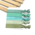 Detail of five green elastic fabric knotted headbands organized on a white display card - Green System