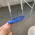 Blue denim style hair clip with black polka dots shown in a hand-held close-up view - Pencil Shape / Blue with Black Polka Dot Strip