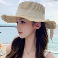 Beige woven straw sun hat with flat top and sweet bow ribbon shown on a beach model - Flat Top Hemp Ribbon Beige Beige