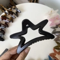 Macro detail of a large matte black hollow star-shaped hair claw clip with frosted texture - 11cm / Matte Black