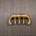 Detailed view of natural sandalwood five-tooth scalp massage comb on bamboo mat - Golden Sandalwood Crown Shape (9.8*5.5*2cm)