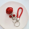 Detail of red cartoon bell keychain with braided strap and metal lobster clasp on ceramic plate - Pure Red