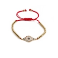 Close-up of red braided rope bracelet with gold beads and inlaid evil eye charm - Evil Eye / Copper Beads Red Rope