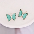 Macro shot of gold butterfly earrings featuring green crystal wings and white zircons - Peacock Green