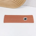 Orange ribbed knit sports headband with black W embroidery on a white surface - Orange