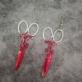 Macro detail of silver scissor earrings with realistic red blood splatter for Halloween - Scissors